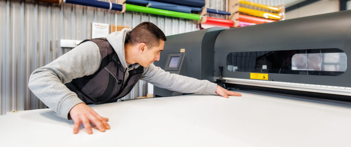 Technician operator works on large premium industrial printer plotter machine